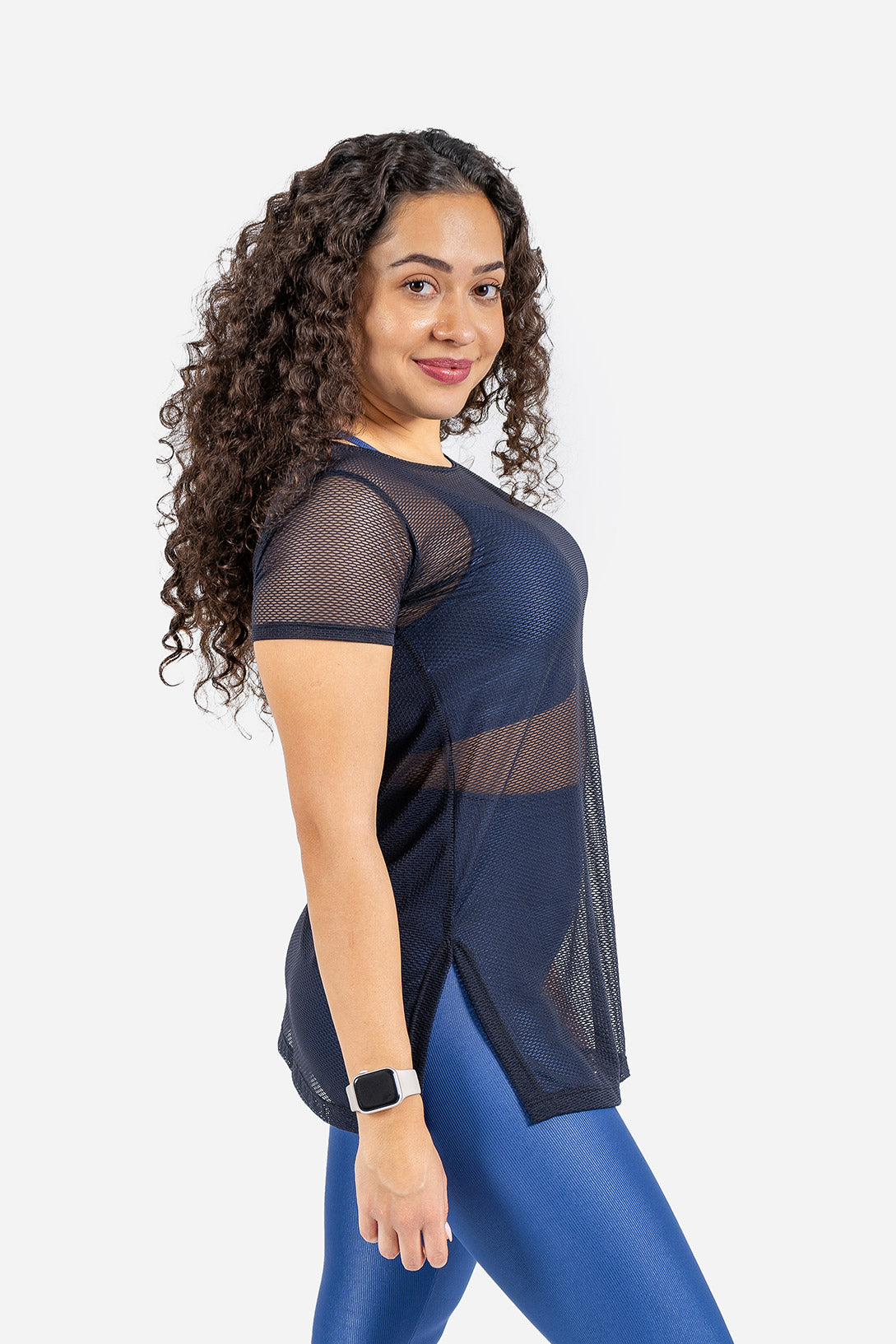 Woman wearing a navy blue mesh top and blue leggings on a white background
