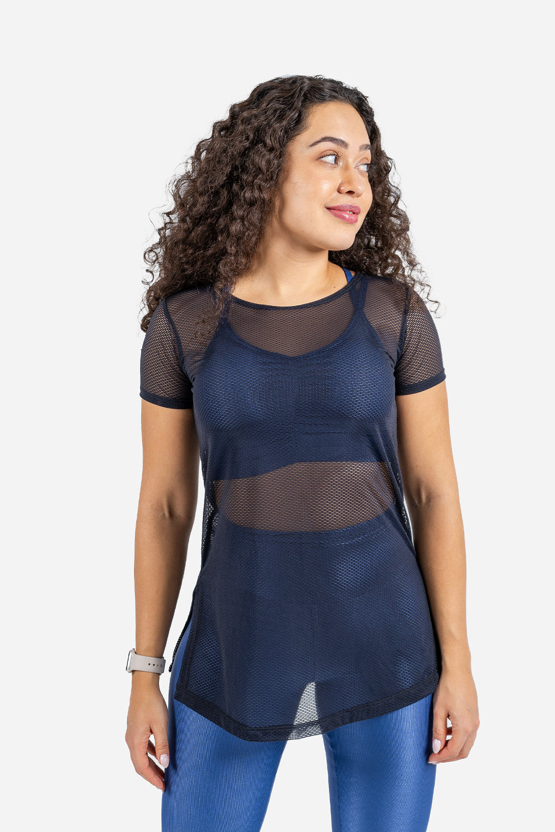 Woman wearing a dark blue mesh top and blue leggings on a white background