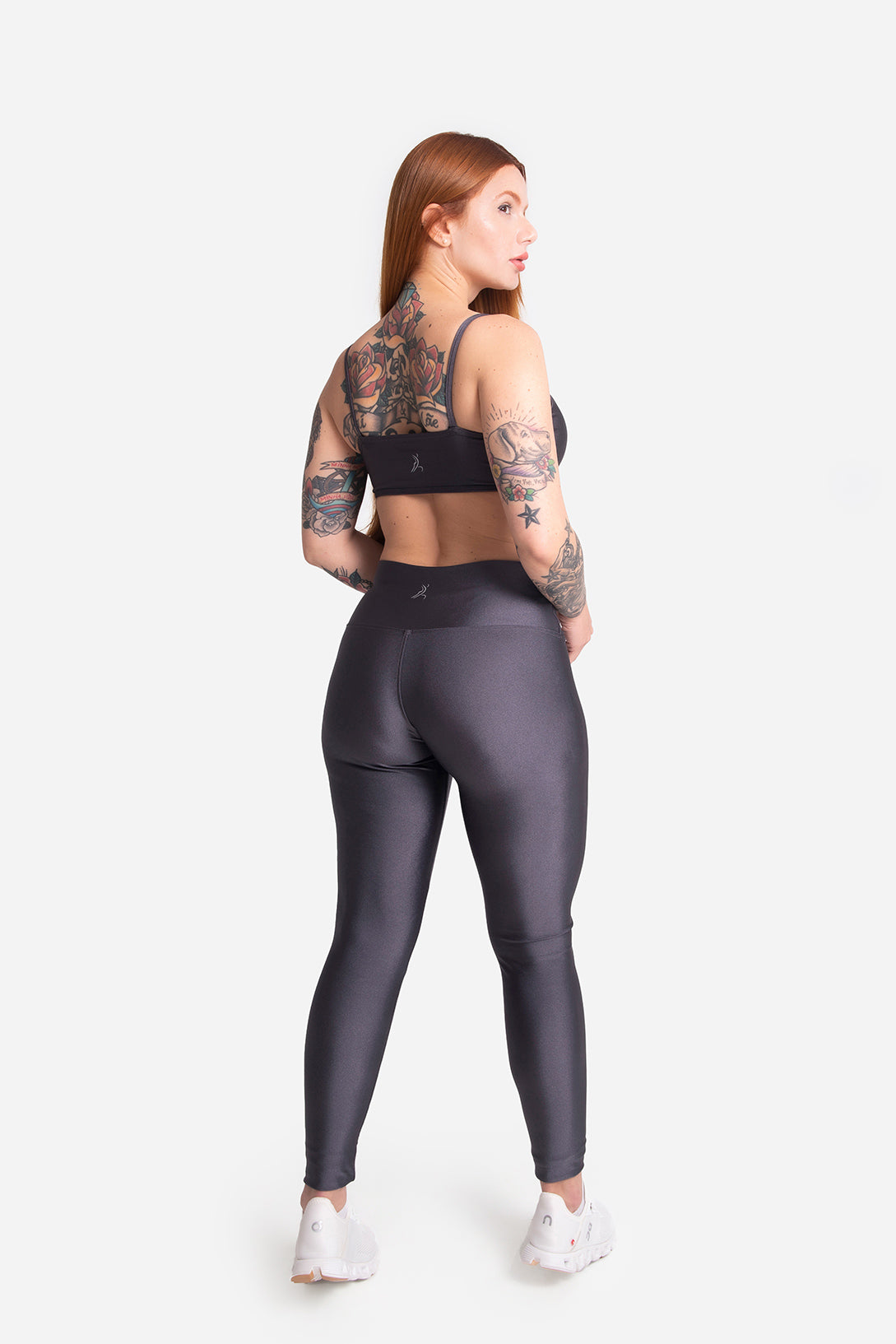 Woman wearing a black sports bra and gray leggings on a white background