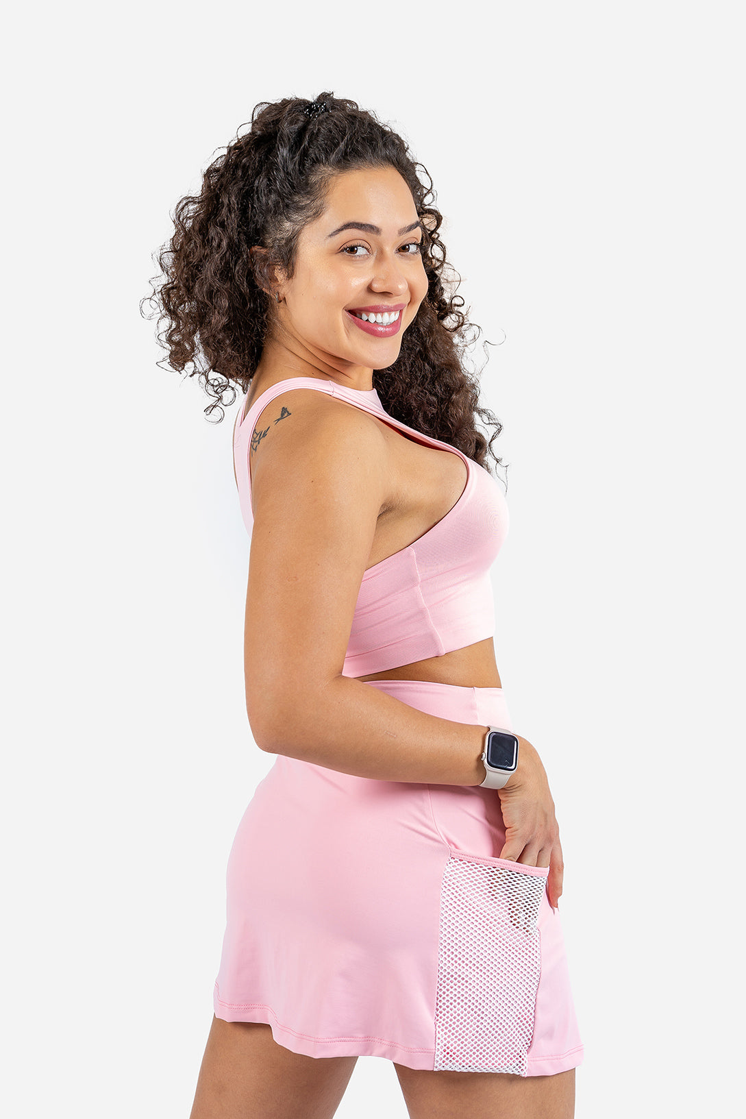 Woman wearing a pink athletic outfit with a white background