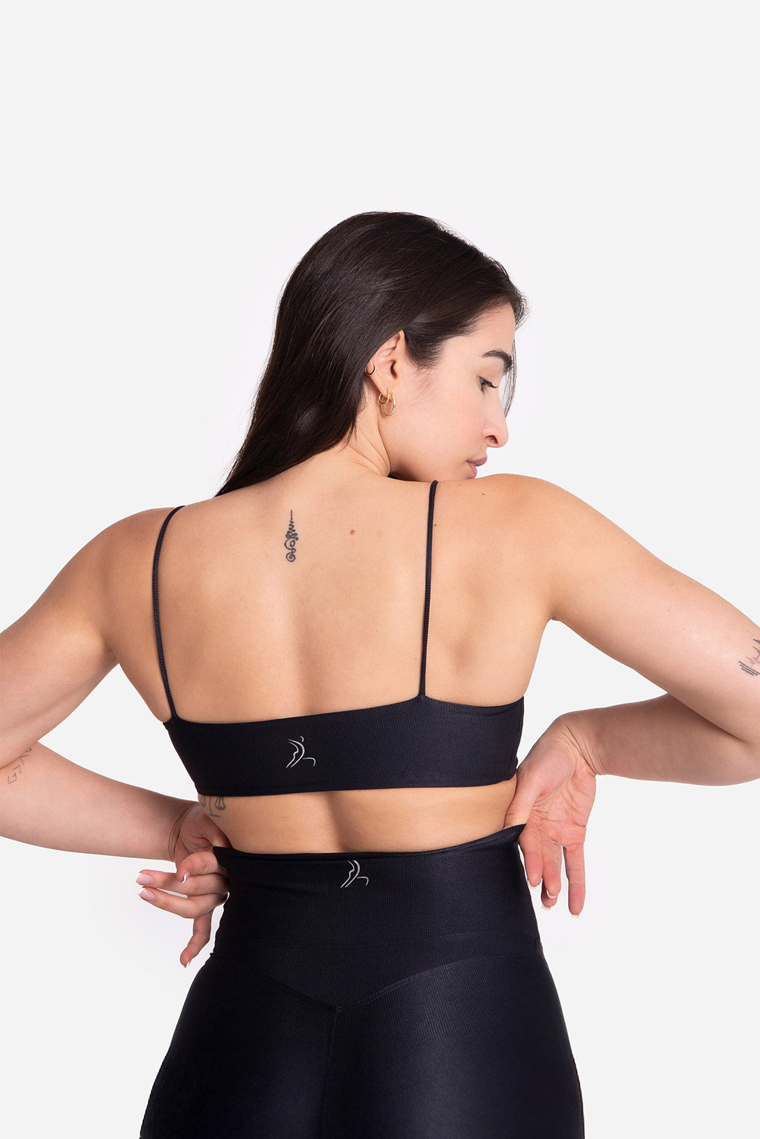 Woman wearing a black sports bra and leggings on a white background