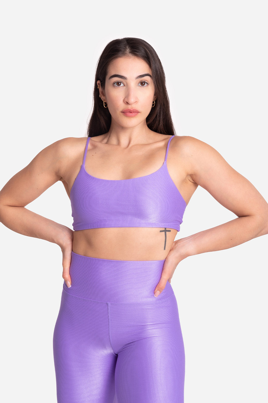 Woman wearing a purple sports bra and leggings on a white background