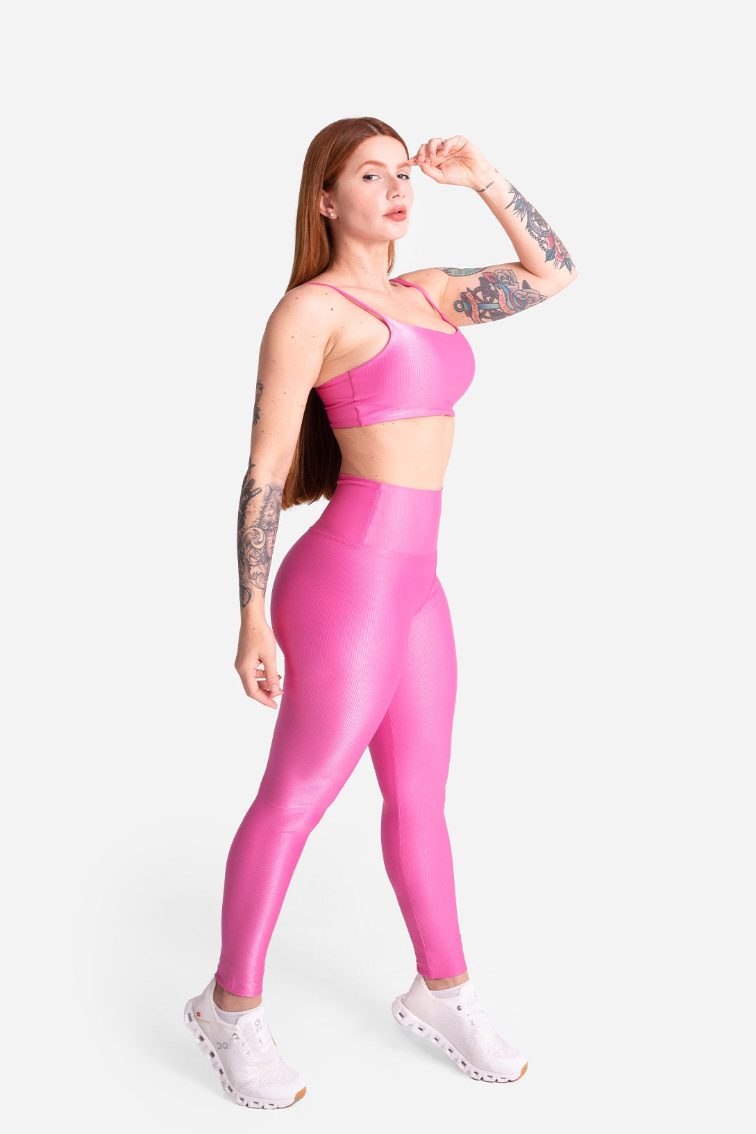 Woman wearing a pink sports bra and leggings set on a white background