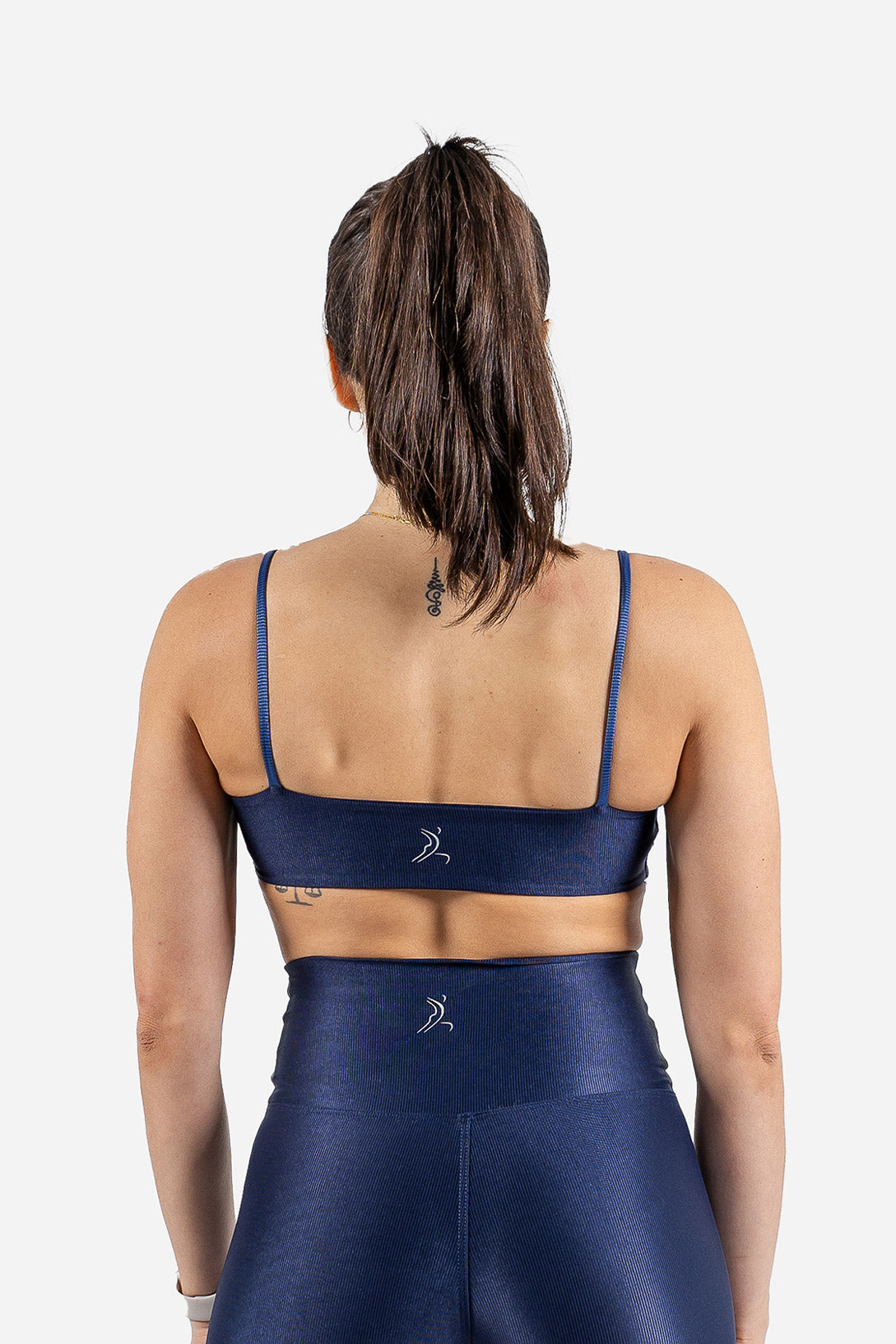 Person wearing a blue sports bra and leggings set on a white background