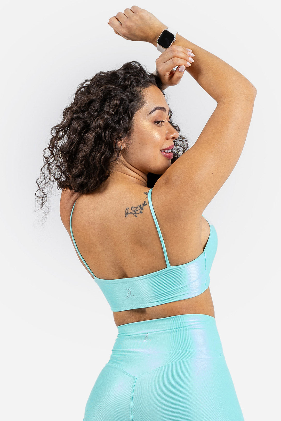 Woman wearing a light blue sports bra and leggings set on a white background