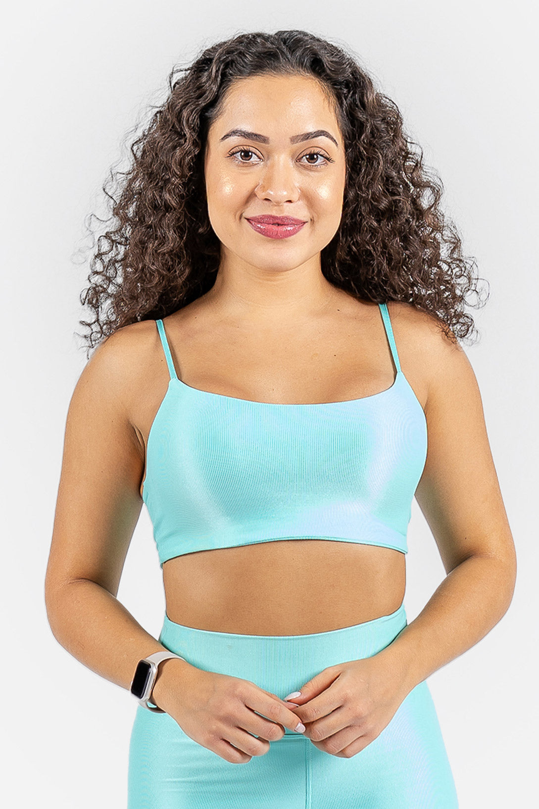 Woman wearing a light blue sports bra and leggings on a white background