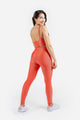 Woman wearing a coral sports bra and leggings set on a white background